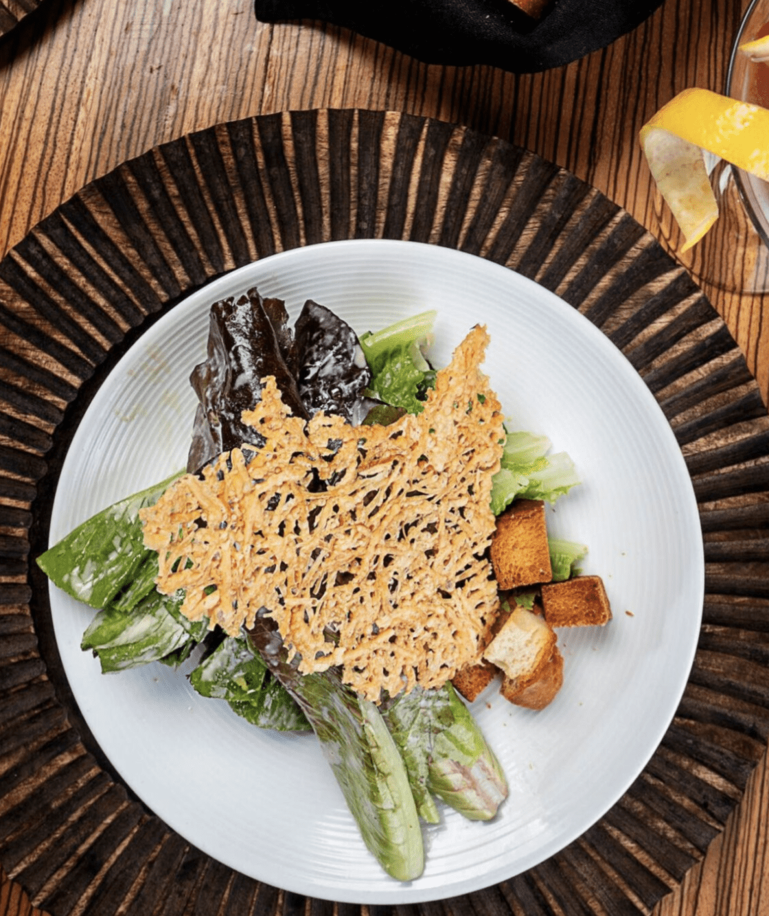 Fresh Caesar-style salad with romaine lettuce, parmesan crisp, and croutons on a white plate