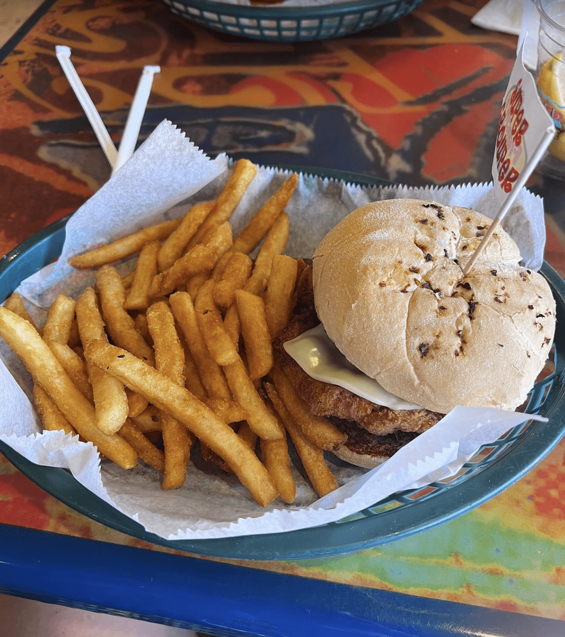 A fried fish sandwich with melted cheese in a toasted bun, served with crispy French fries.