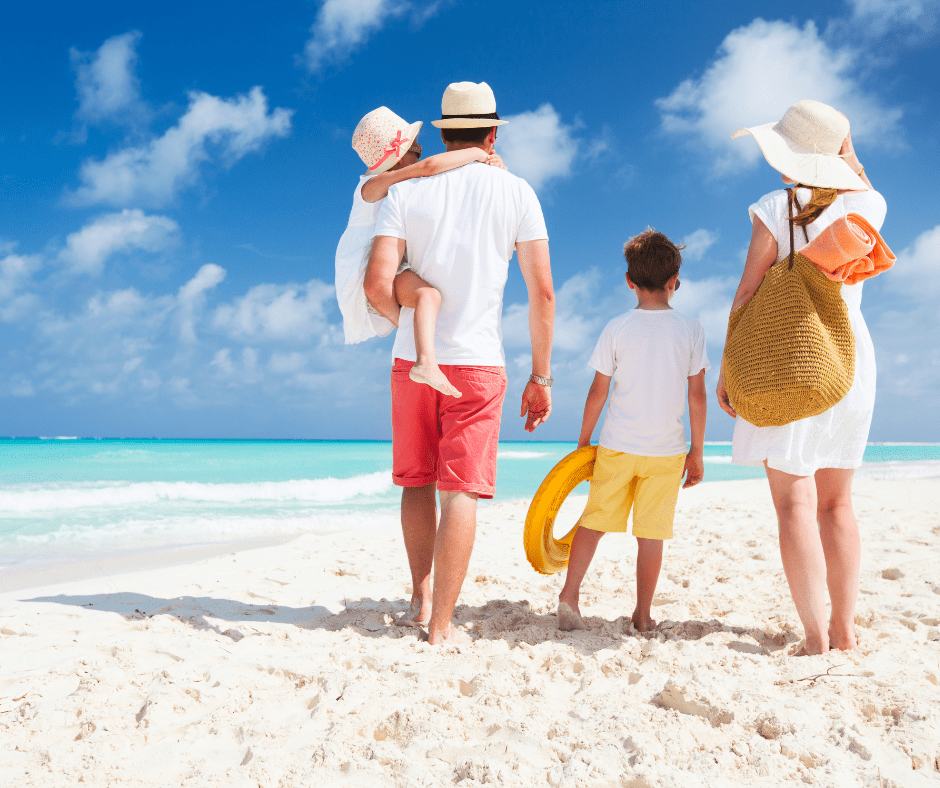 Family walking on the white sandy shore of Clearwater Beach near a vacation rental on a sunny Florida day